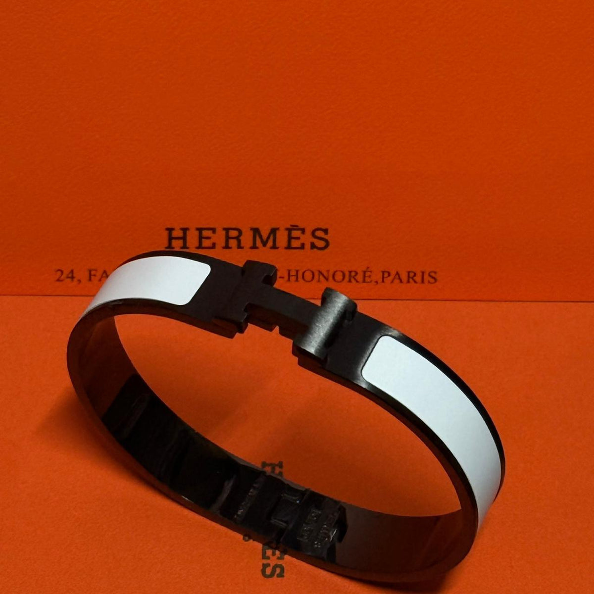 Hermès bracelet on an orange background with brand name visible