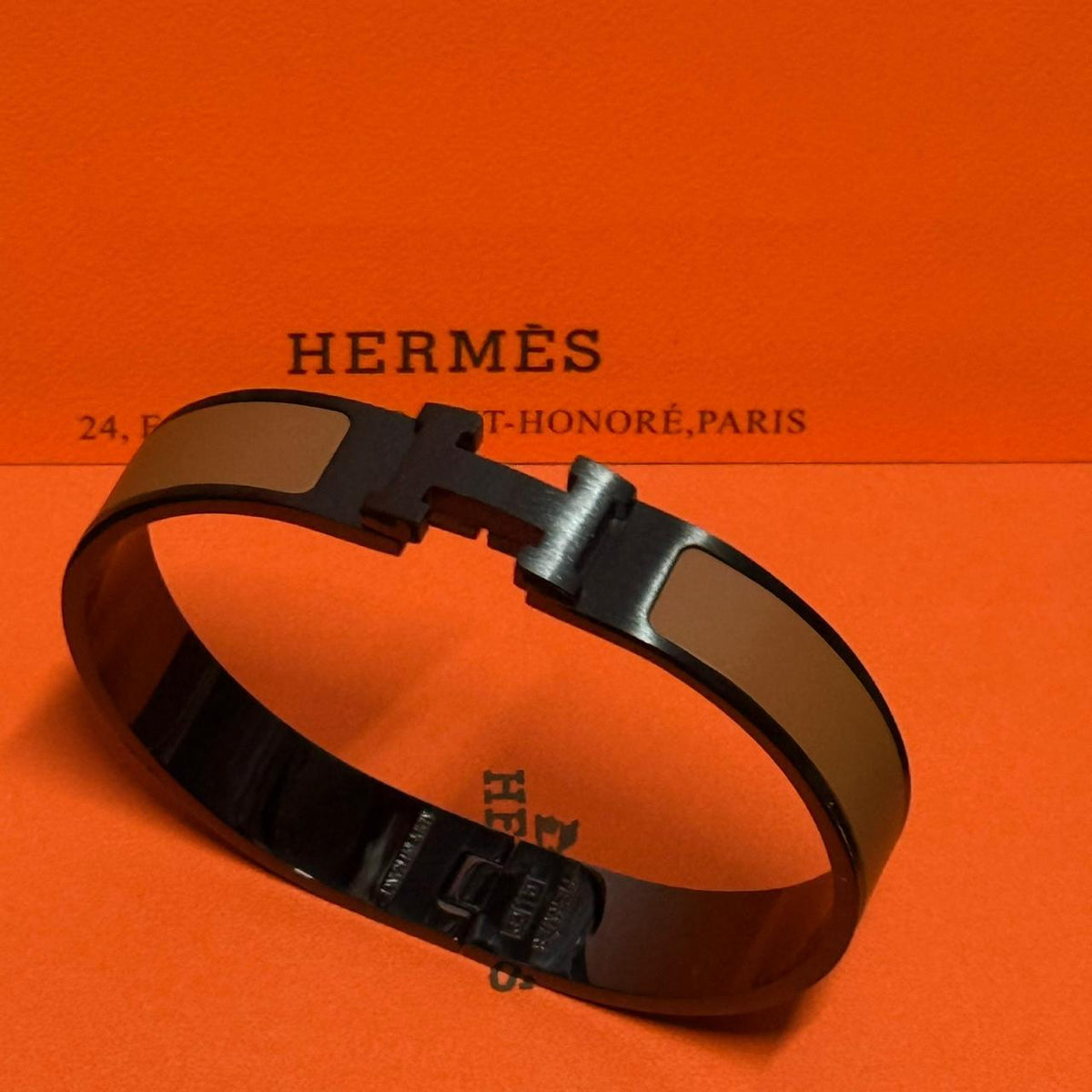 Hermes bracelet on an orange background with brand name visible