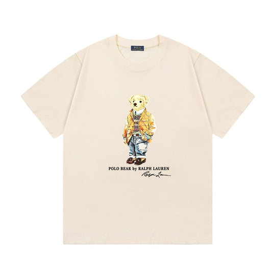 A cream-colored short-sleeve t-shirt featuring a central graphic of the iconic Polo Bear wearing a yellow jacket and blue jeans, with 'POLO BEAR by KALPI LAUREN' printed below.