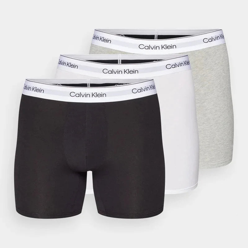 Four pairs of Calvin Klein boxer briefs in black, white, and gray on a white background.