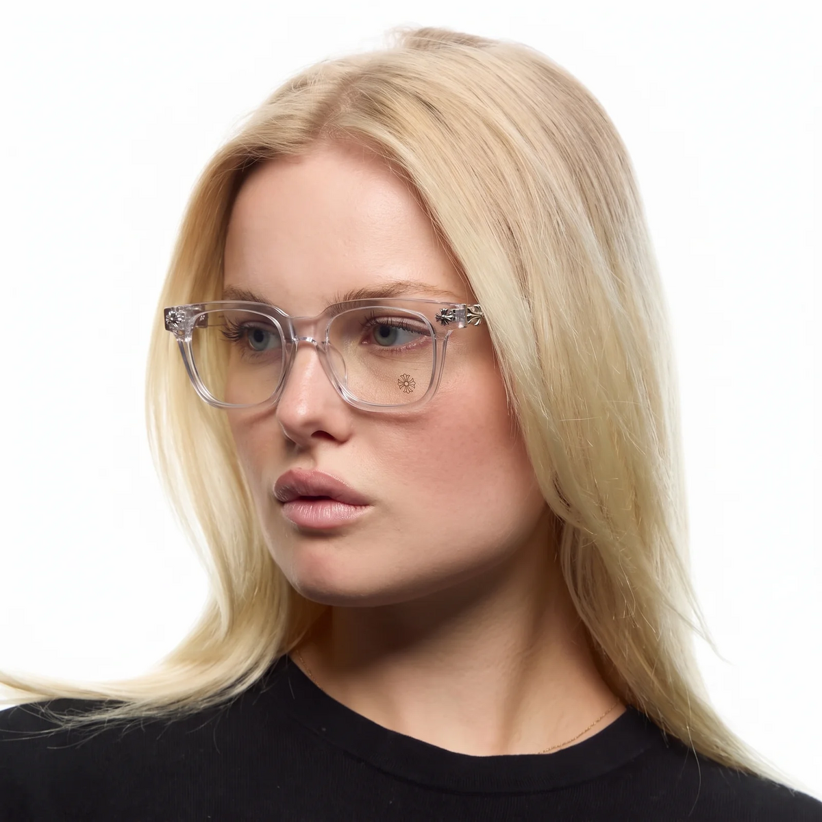 A blonde woman wearing clear acetate square eyeglasses with decorative silver-toned metal hinges, shown in a close-up portrait against a white background.