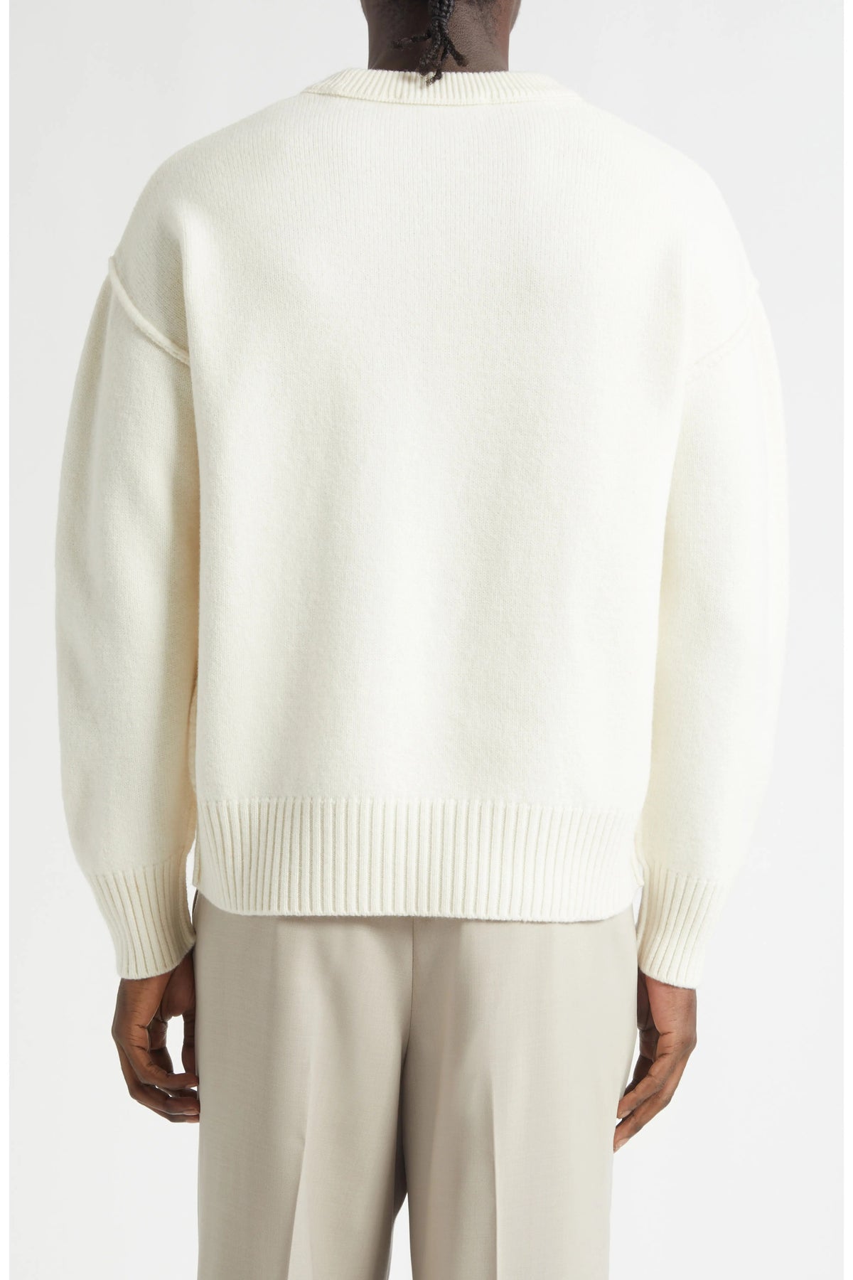 Person wearing a cream sweater and beige pants on a white background