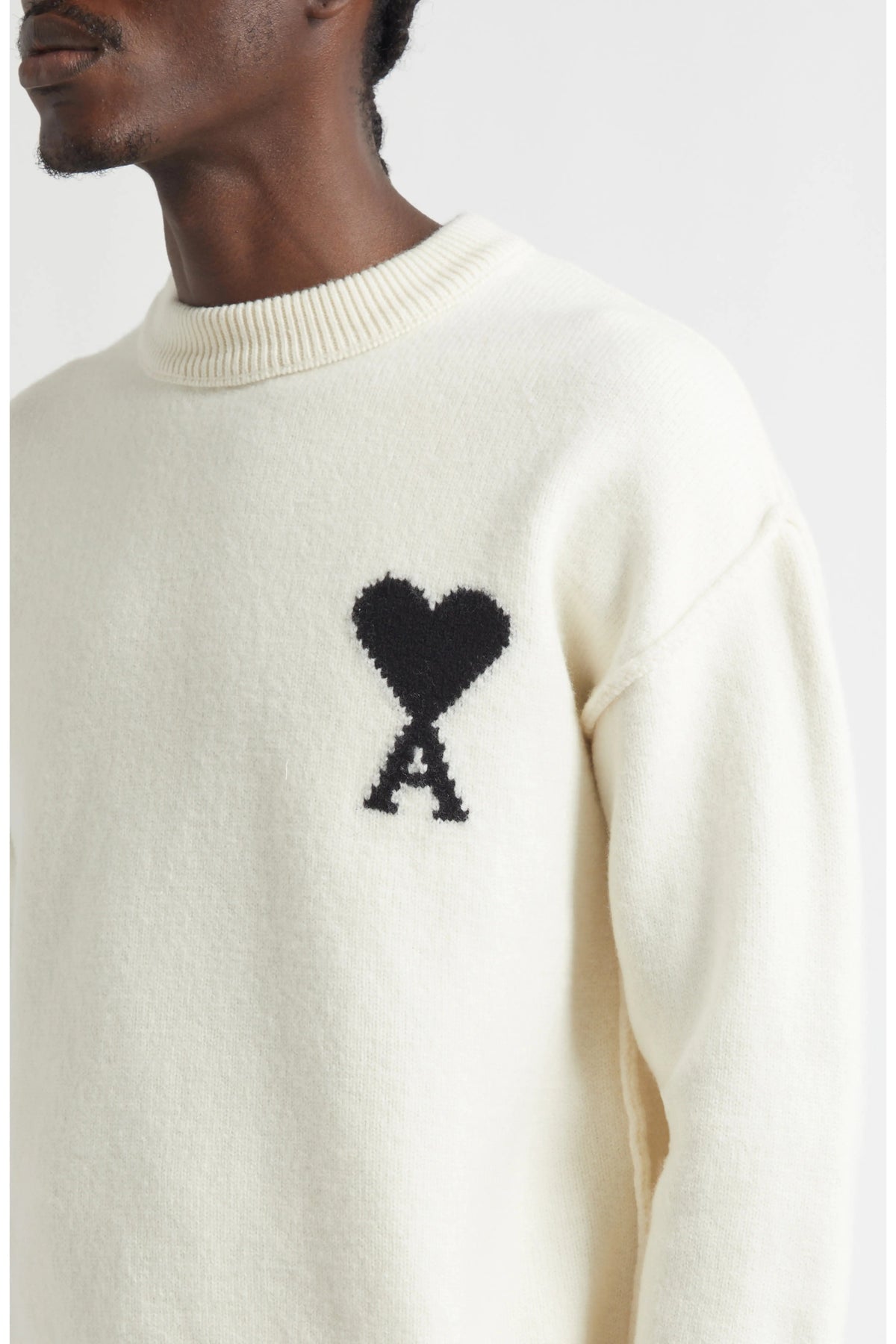 White sweater with black heart and 'A' design on a neutral background