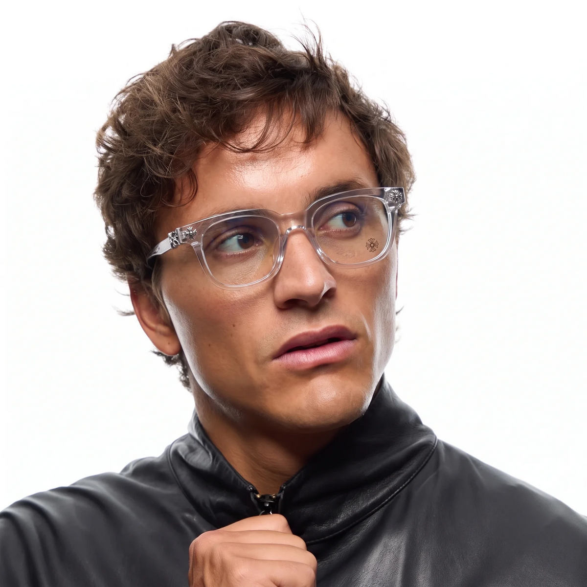 A close-up portrait of a man with short brown hair wearing clear-framed eyeglasses and a black leather jacket, looking off to the side against a plain white background.